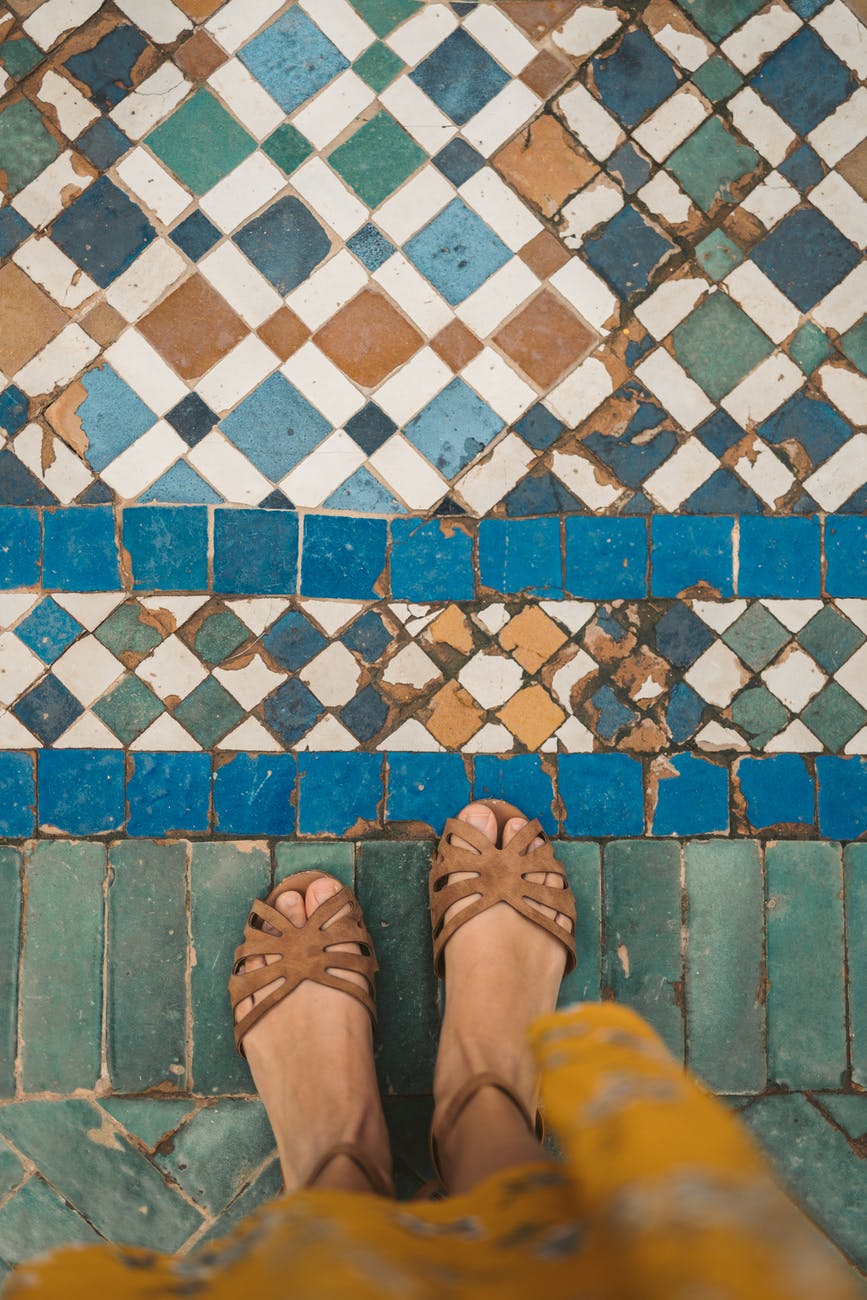 person in sandals standing on blue and white floor tiles